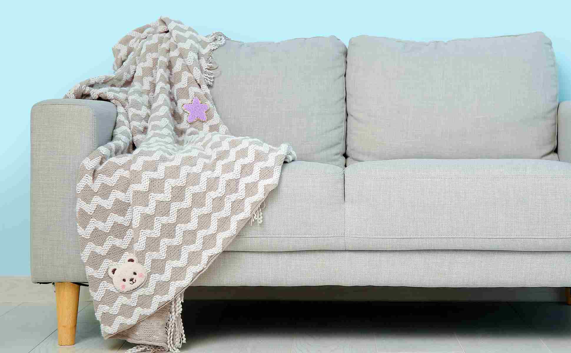 A grey couch with a blanket on it showcasing iron on patch ideas 